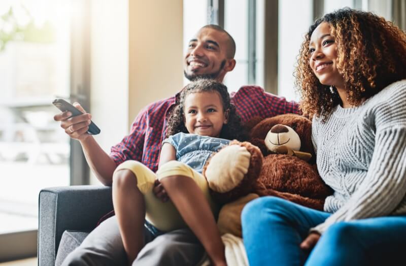 Family in living room watching tv with remote